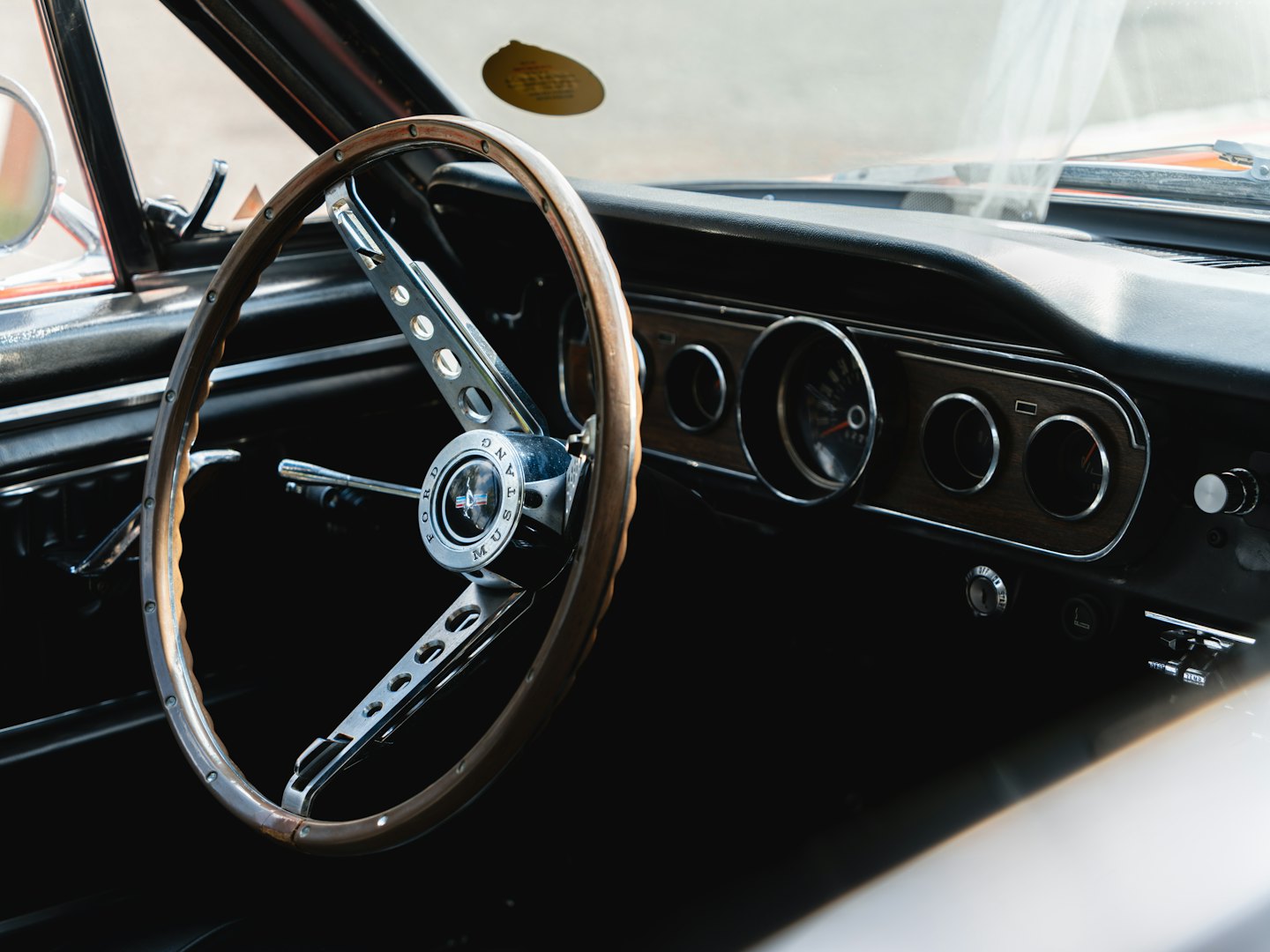 Klassisches Holzlenkrad und Armaturenbrett in einem Oldtimer.