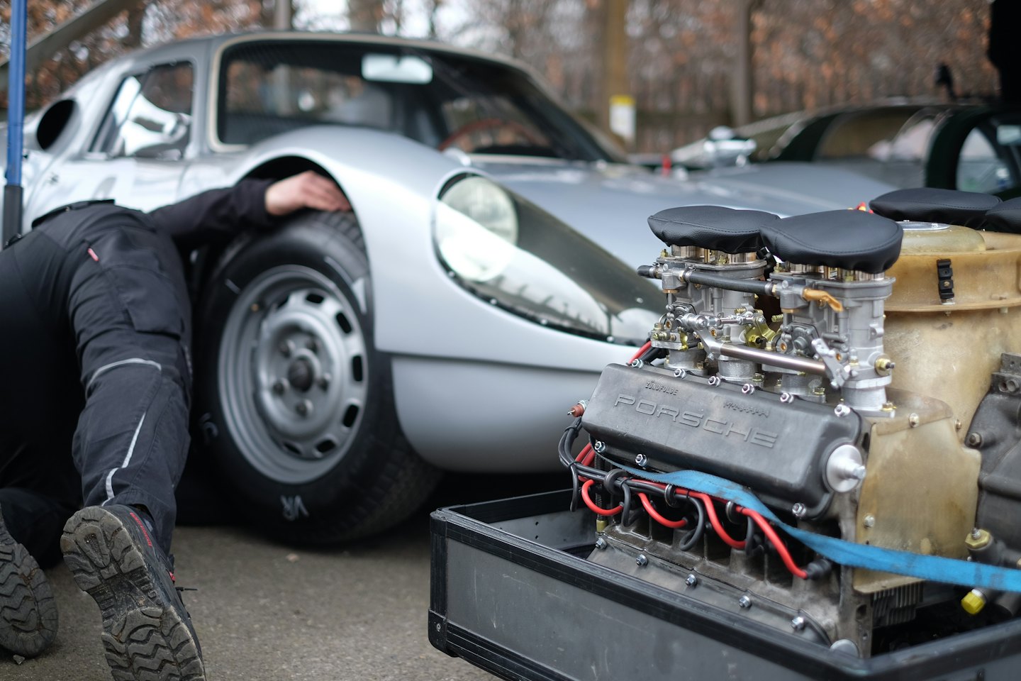 Mechaniker arbeitet am Vorderrad eines Oldtimer-Sportwagens.