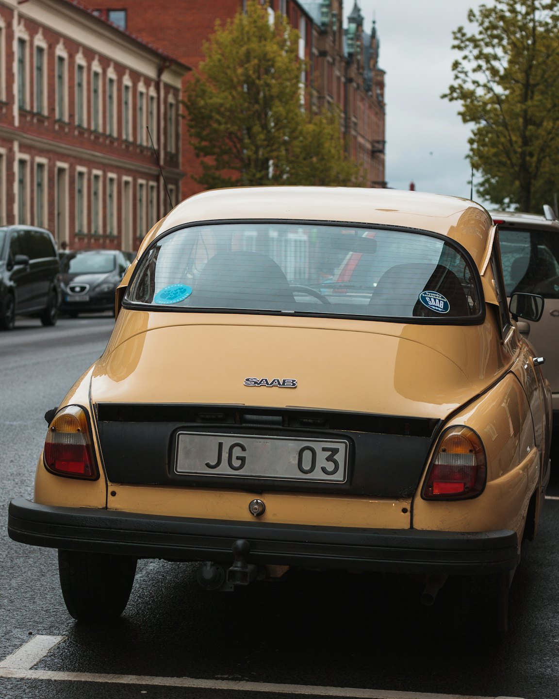 Gelber Oldtimer-Saab auf nasser Stadtstraße.
