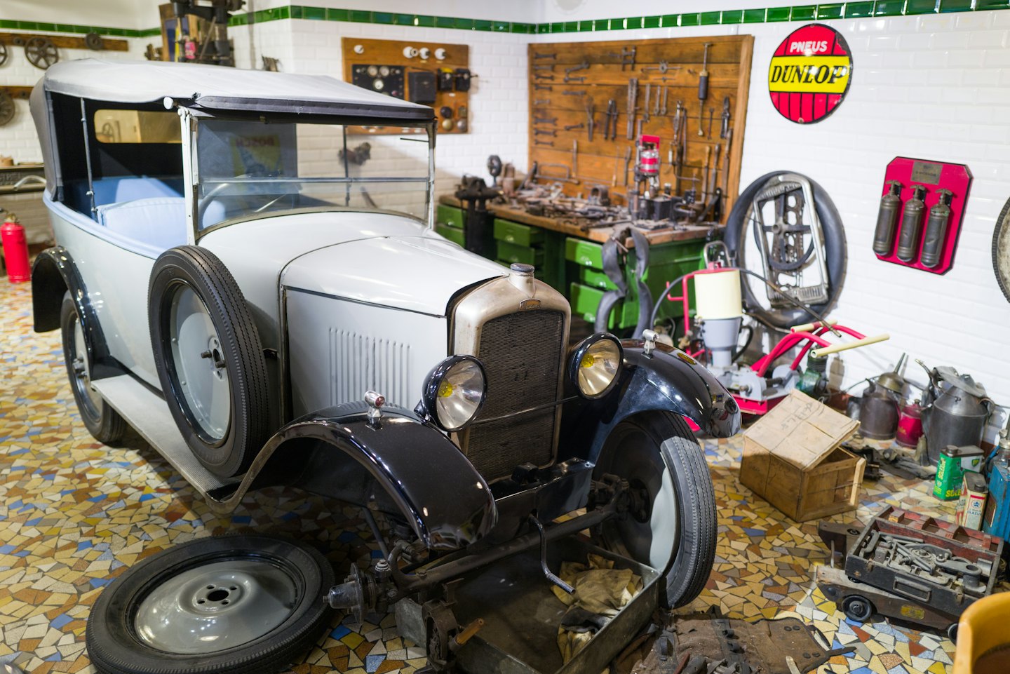 Oldtimer mit ausgebauter Vorderachse in einer Werkstatt.